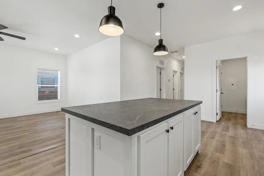 Kitchen island with dark countertop and pendant lights