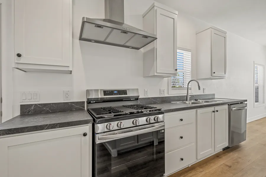 Kitchen with white cabinets, stainless steel gas range and range hood